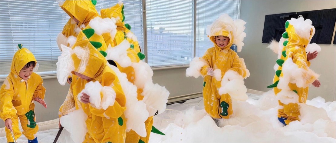 Children enjoying a playful foam activity in yellow raincoats